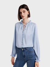 a lady in a light blue silk ruffle blouse